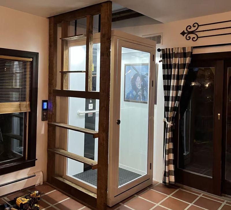 A white home elevator installed on the corner of a house